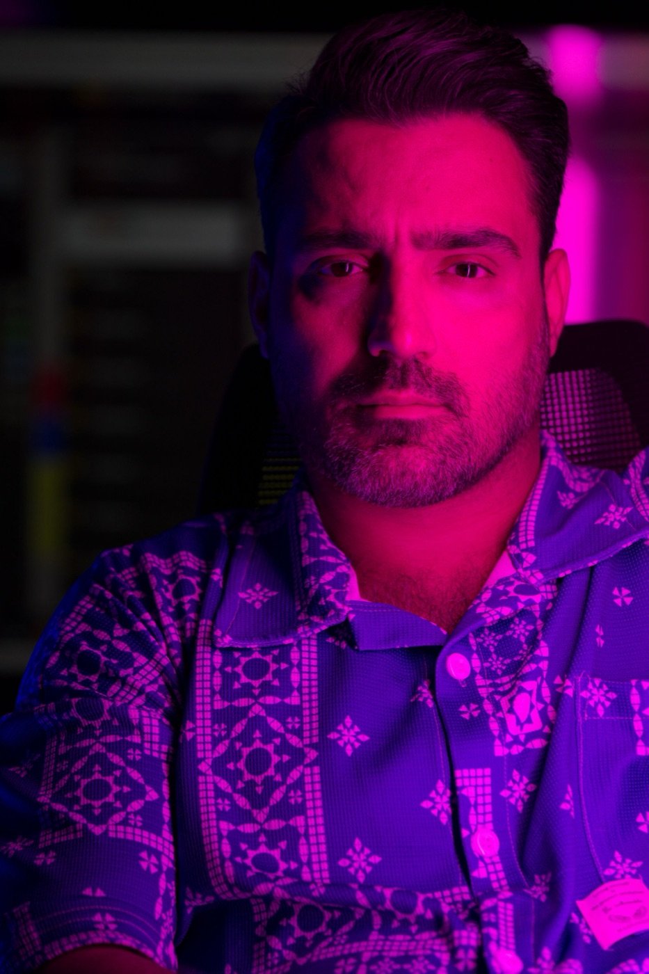A man in pink and violet light, looking straight at you