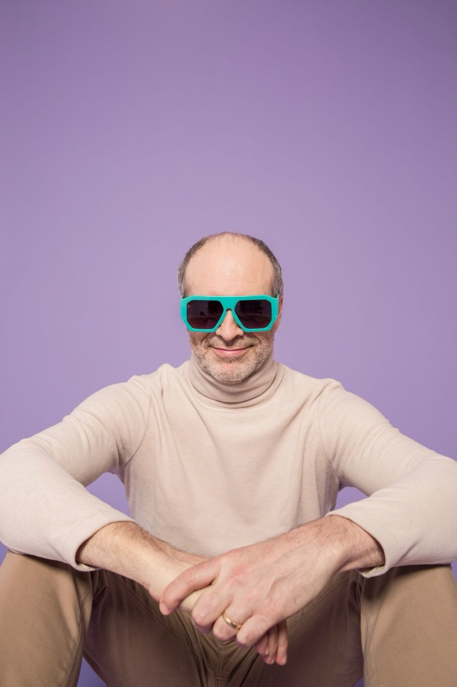 A man in teal sunglasses on lilac
