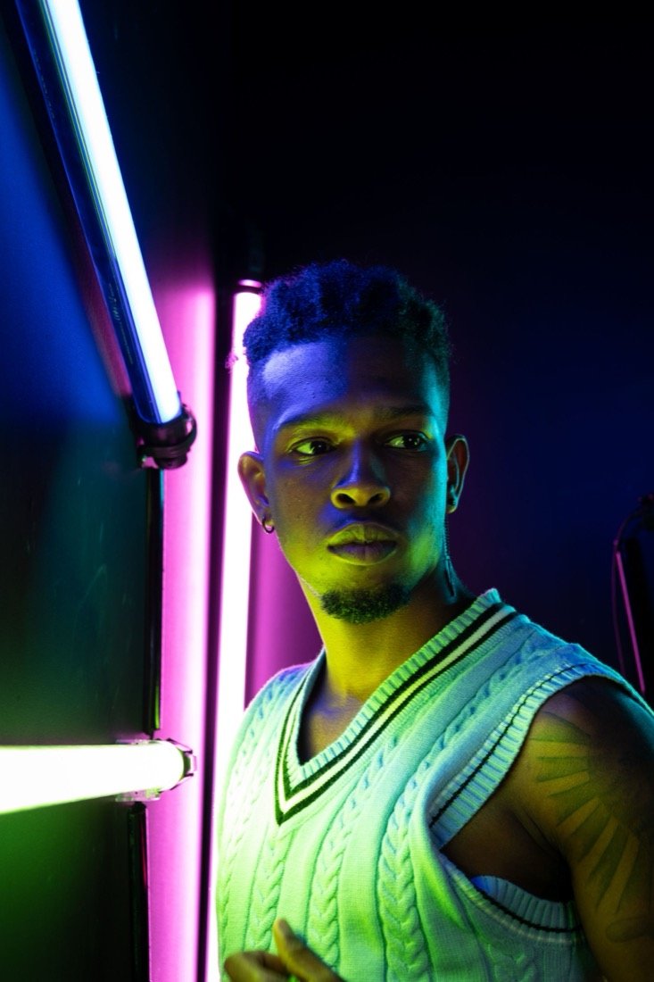 A young man between magenta and green neon tubes